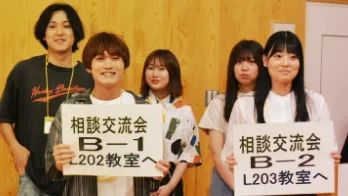 オープンキャンパス時に相談交流会のプラカードを持った男女の学生5名